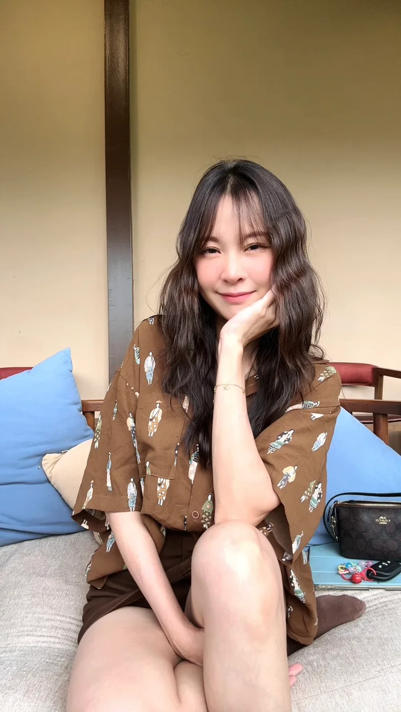 Nilin — Baan Vintage live show host, smiling warmly on a sofa